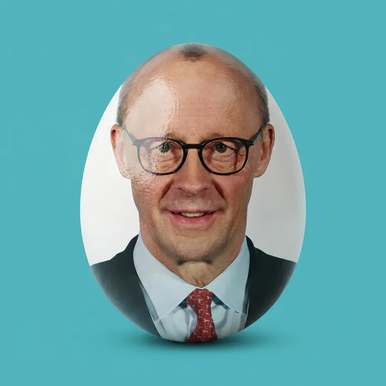 Ein weißes Ei, auf dessen Schale ein Porträt von Friedrich Merz gedruckt ist. Noch ist es heil.